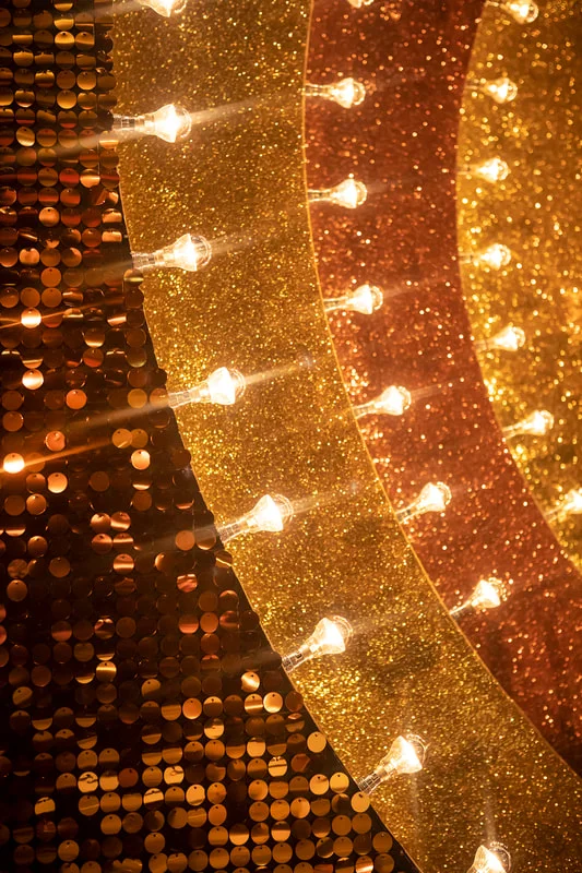 Detalhe de iluminação cenográfica em sequência de lâmpadas — luz dourada criando atmosfera dramática em ambiente comercial
