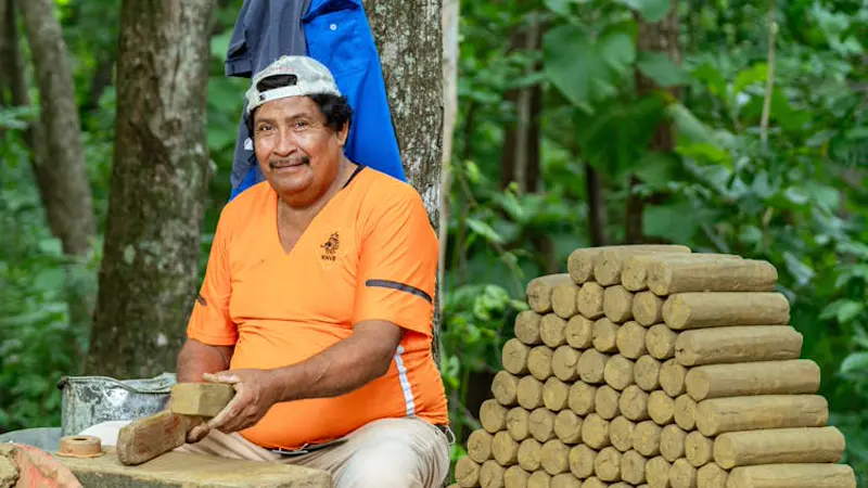 Homem moldando tijolos de adobe artesanalmente — mistura de barro e fibras vegetais em ambiente rural