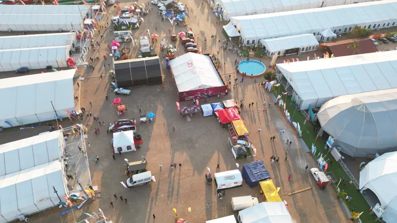 Vista aérea de feira ao ar livre com pavilhões modulares brancos e grande público — exemplo de arquitetura efêmera em evento