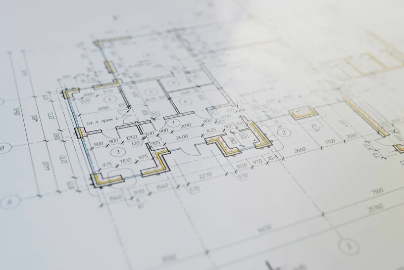 Engenheiro analisando planta baixa hidráulica sobre bancada de projetos com traçado de ramais de água e esgoto
