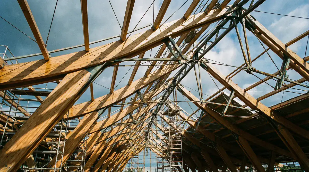 Estrutura de telhado em obra: tesouras de madeira montadas vencendo grande vão livre, vista interna