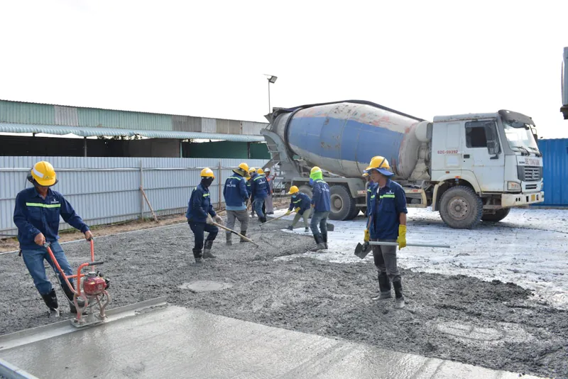 Trabalhadores lançando concreto com caminhão betoneira na execução de fundação radier em obra