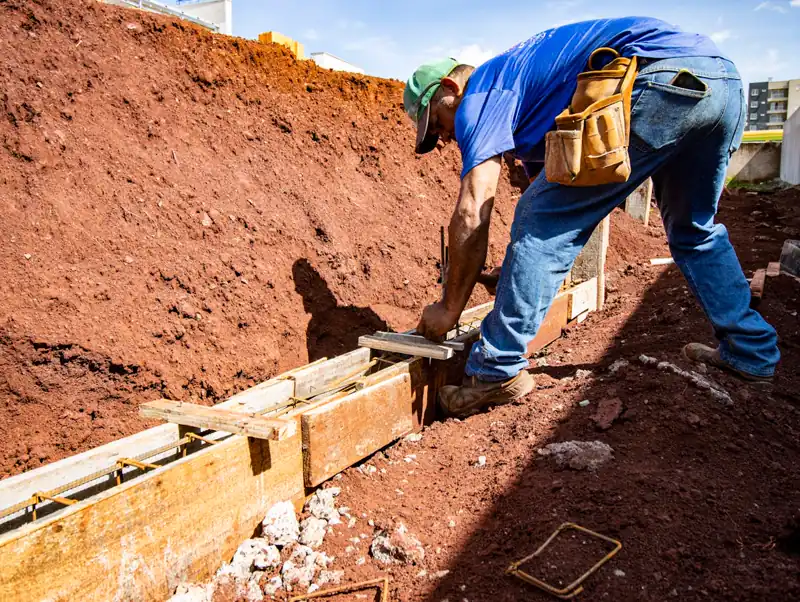 Trabalhador de construção civil em execução de fundação radier em obra residencial no Brasil