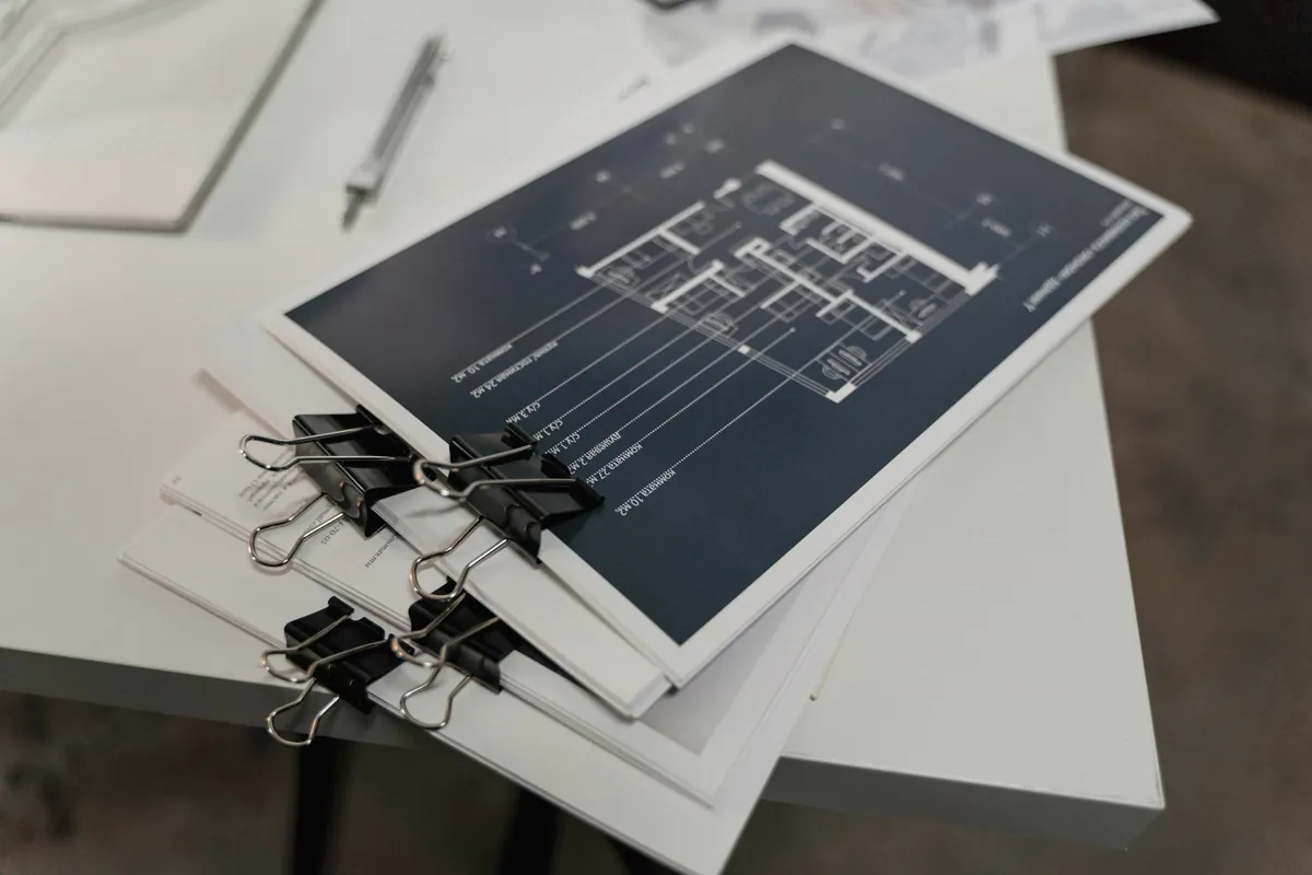 Mesa de trabalho com documentos técnicos de arquitetura, plantas e memorial descritivo