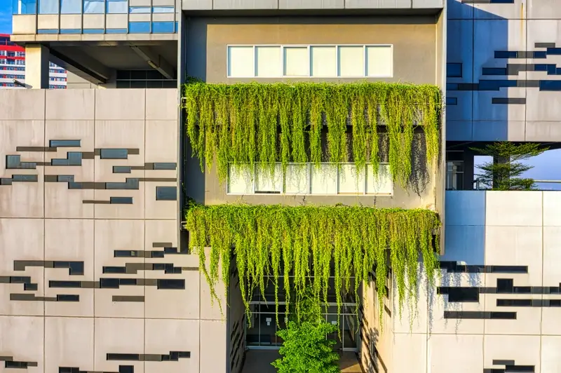 Fachada de edifício sustentável com parede verde — vegetação cascata integrada à arquitetura como tecnologia passiva