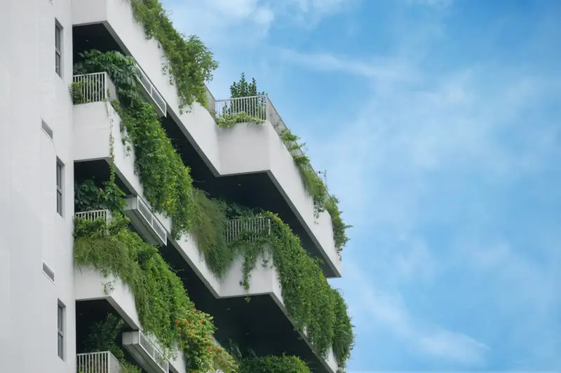 Edifício moderno com terraços verdes e vegetação abundante nos andares — exemplo de telhado verde e paredes verdes em arquitetura sustentável