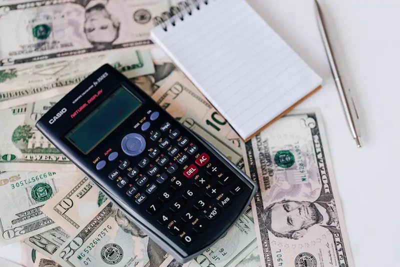 Calculadora sobre notas de dinheiro representando planejamento financeiro de obra