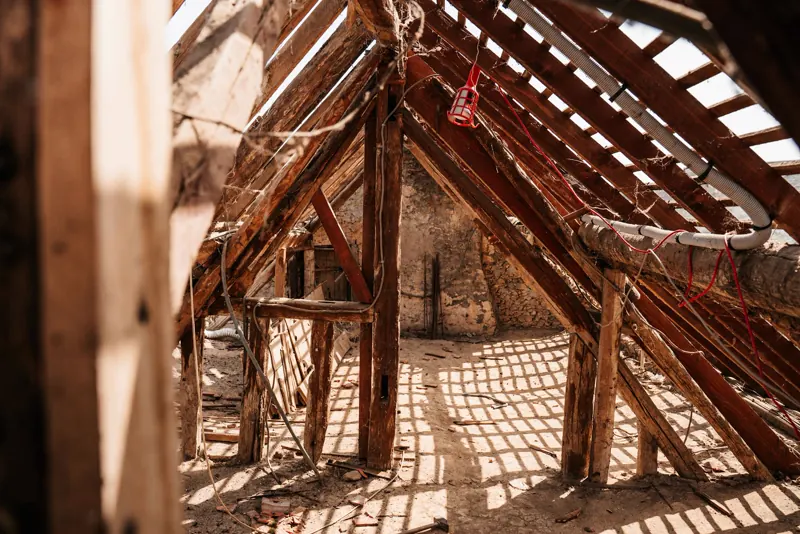 Estrutura de madeiramento de telhado colonial com tesouras, terças e caibros de madeira